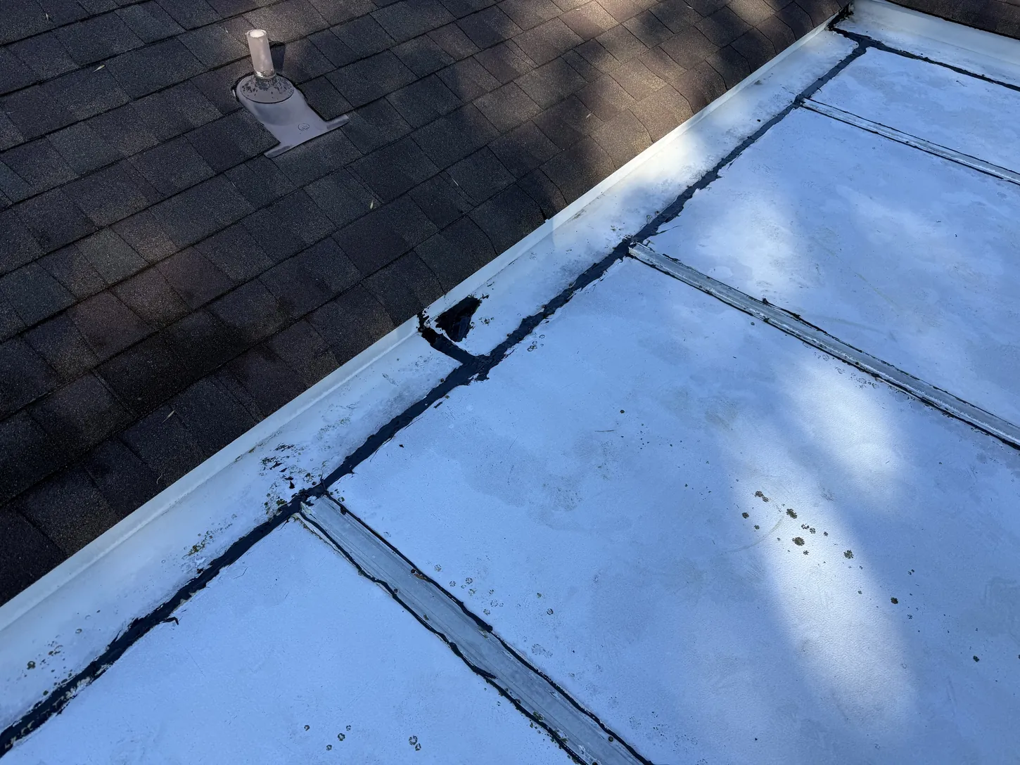 Before: failing seams on a low-slope flat roof next to shingles